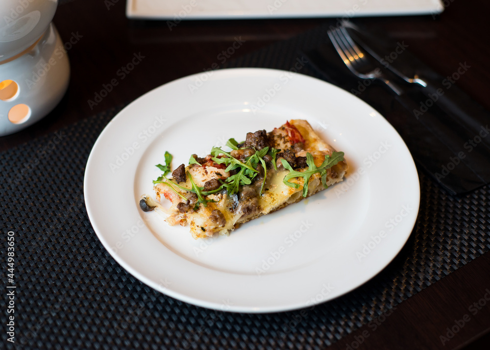slice of pizza on a white plate in a cafe slice of pizza on a white plate in a cafe
