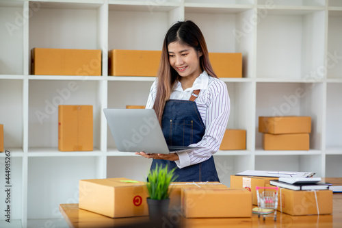 Starting Small business entrepreneur SME freelance,Portrait young woman working at home office, BOX,smartphone,laptop, online, marketing, packaging, delivery, SME, e-commerce concept © David