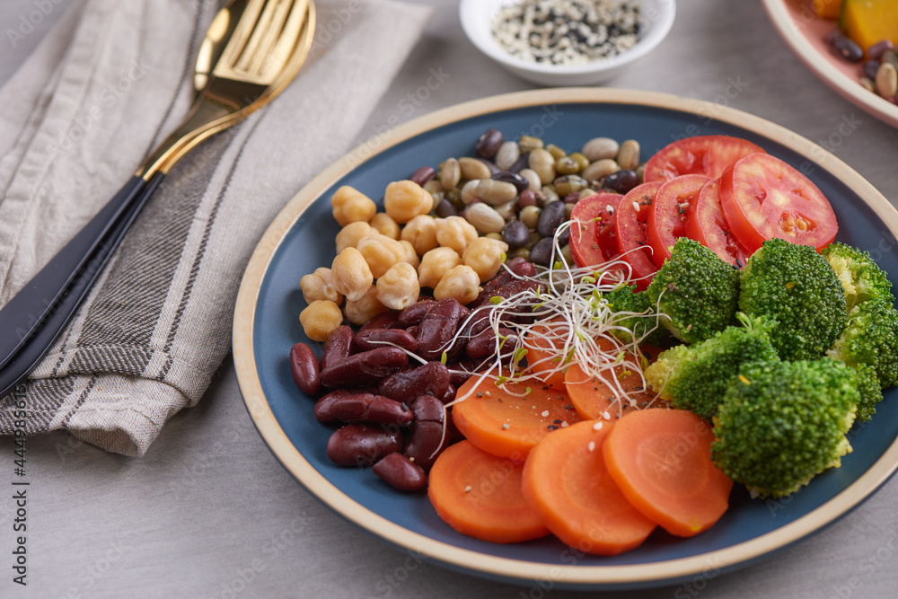 Healthy vegan lunch bowl, buddha bowl salad with ingredients. chickpeas, various nuts and tomatoes, broccoli, carrots . Healthy balanced vegetarian food concept. Top view.