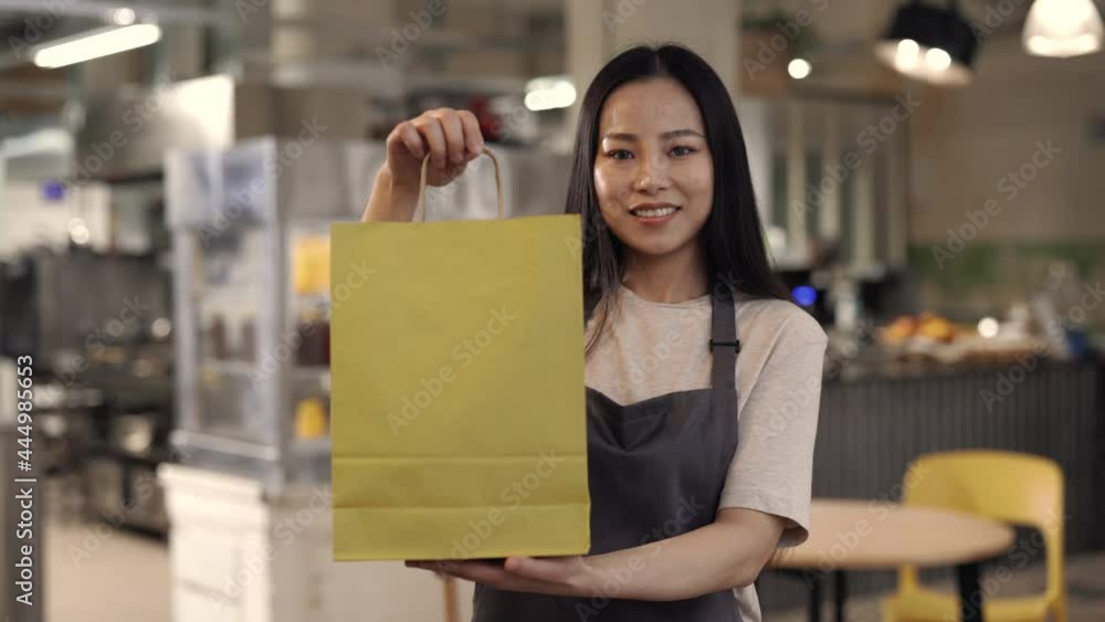 Pretty asian waitress preparing takeaway meal at cafe Pretty asian waitress preparing takeaway meal at cafe