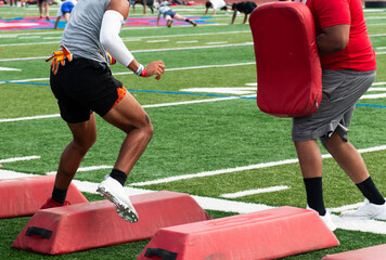Football player running sideways over red barriers at summer camp