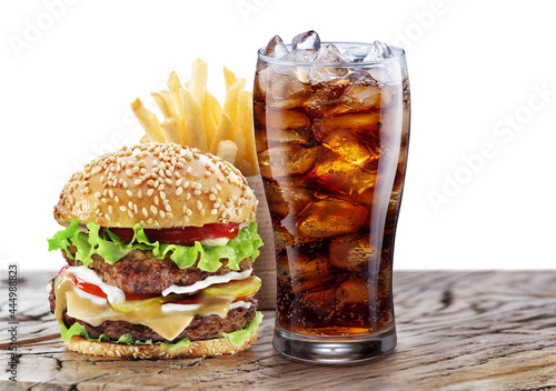 Delicious hamburger with cola and potato fries isolated on wooden table and on white background. Fast food concept.