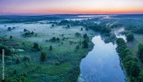 Smoky morning mist over the river. Beautiful panoramic view of river and green banks of the river in the early summer morning.