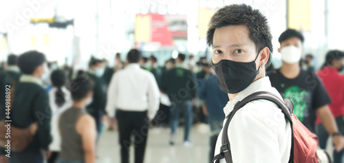 Asian businessman in airport terminal, wears medical mask during covid-19 or coronavirus crisis. vacation or travel concept. airport of Thailand, man holding passport, boarding pass and smart phone. 