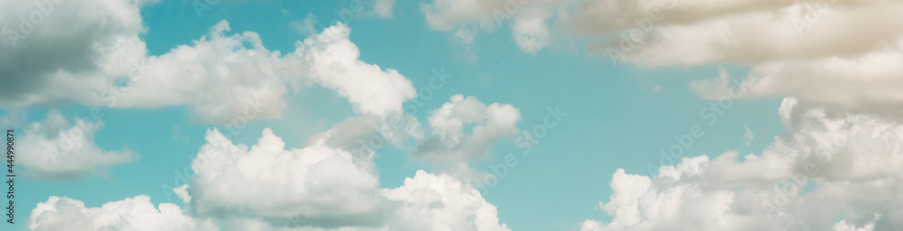 Banner. Background of a blue sky with large white clouds. Summer atmospheric background. Warm saturated colors Banner. Background of a blue sky with large white clouds. Summer atmospheric background. Warm saturated colors