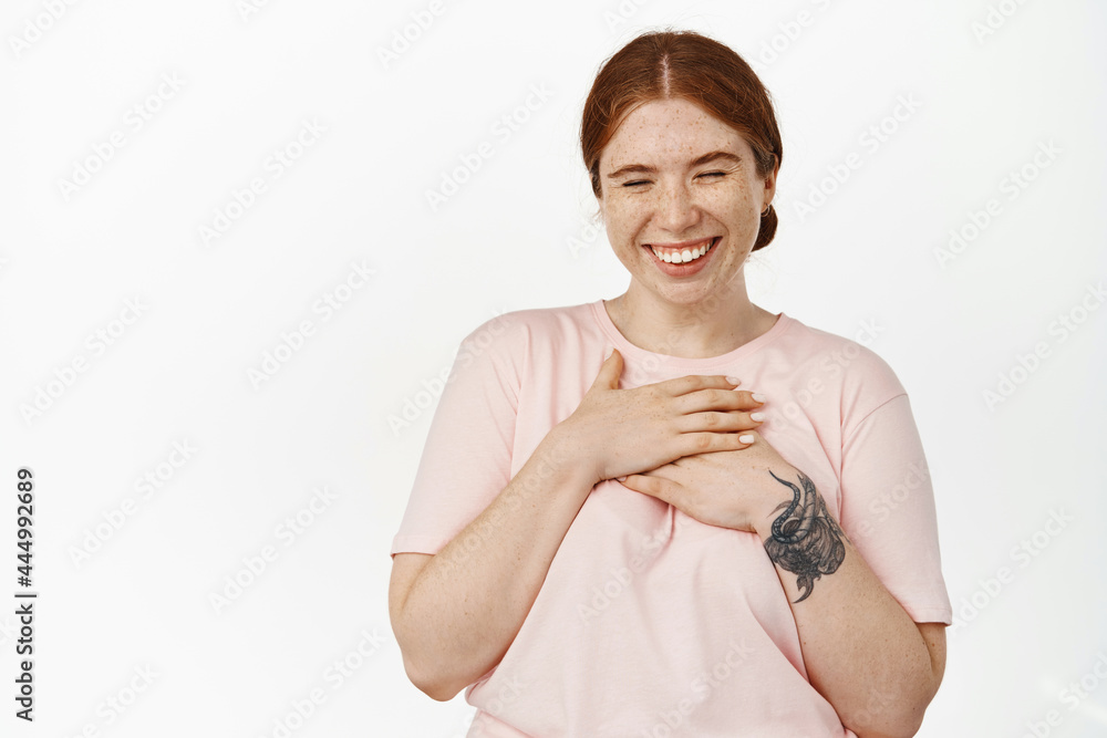 Image of carefree young woman with red combed hair and freckles, holding hands on chest, laughing sincere and smiling white teeth, positive emotions and face expression, white background Image of carefree young woman with red combed hair and freckles, holding hands on chest, laughing sincere and smiling white teeth, positive emotions and face expression, white background