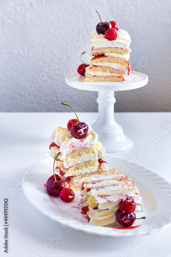 Raspberry tiramisu, layers of sponge, cream and fruit sauce. Decorated with fresh raspberries and cherries.