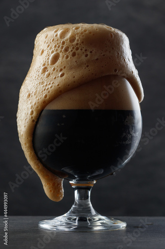 Photo Detail of dark beer with overflowing foam head