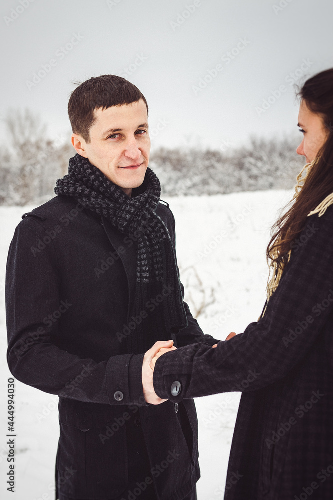 A guy and a girl in warm clothes and scarves on a walk in the snowy weather A guy and a girl in warm clothes and scarves on a walk in the snowy weather