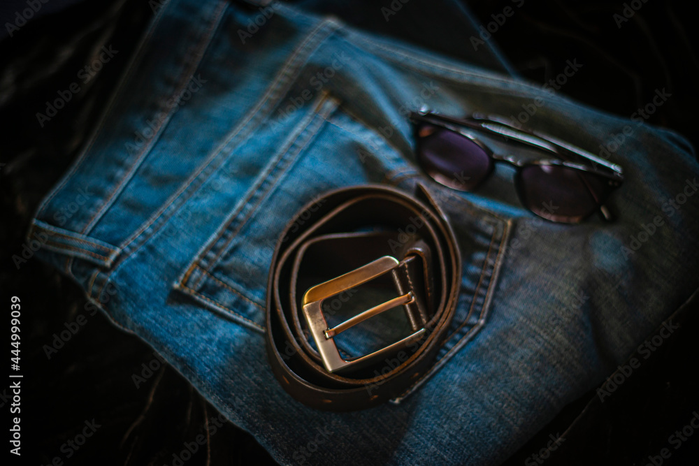 leather belt is a casual wardrobe accessory. Beautiful leather belt and jeans close-up. Men's brutal accessories, belt on a dark background with blurred depth of field, brown belt and denim leather belt is a casual wardrobe accessory. Beautiful leather belt and jeans close-up. Men's brutal accessories, belt on a dark background with blurred depth of field, brown belt and denim
