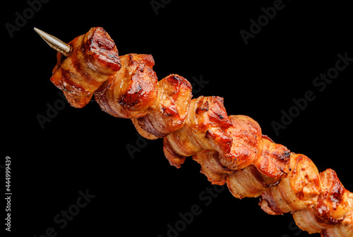 Barbecue turkey breast with bacon on skewers on black background. Brazilian gastronomy.