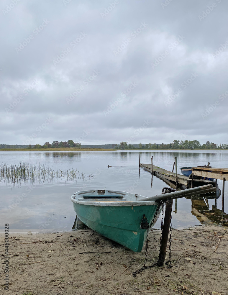 Rowing boat on the shores of Lake Seliger. Walkway on a sandy beach on a cloudy day