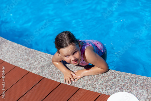 a happy child jumps on the edge of the pool and enjoys a hot sunny day. 