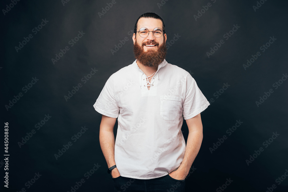 Bearded man on dark background. Stylish man wearing glasses, looking at camera and smiling