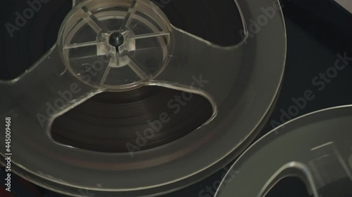 Close up of bobbin. Reel film tape is rotating at a vintage player. Reel to reel tape recorder playing. Popular Disco Trends 60s, 70s, 80s, 90s. Old school concept.