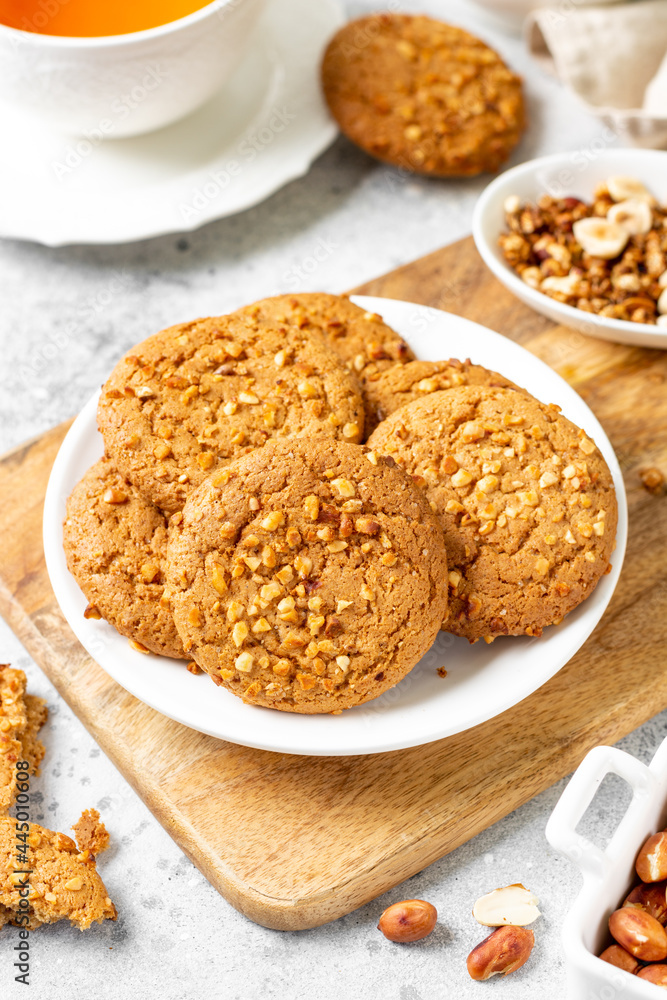 Healthy homemade oatmeal cookies with peanuts in a white plate on a light gray kitchen table closeup Healthy homemade oatmeal cookies with peanuts in a white plate on a light gray kitchen table closeup