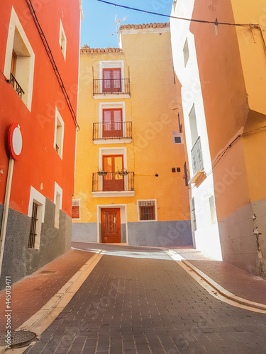 Mufti-colored highly decorated homes line narrow street Villa Joyosa, Alicante Spain. photo