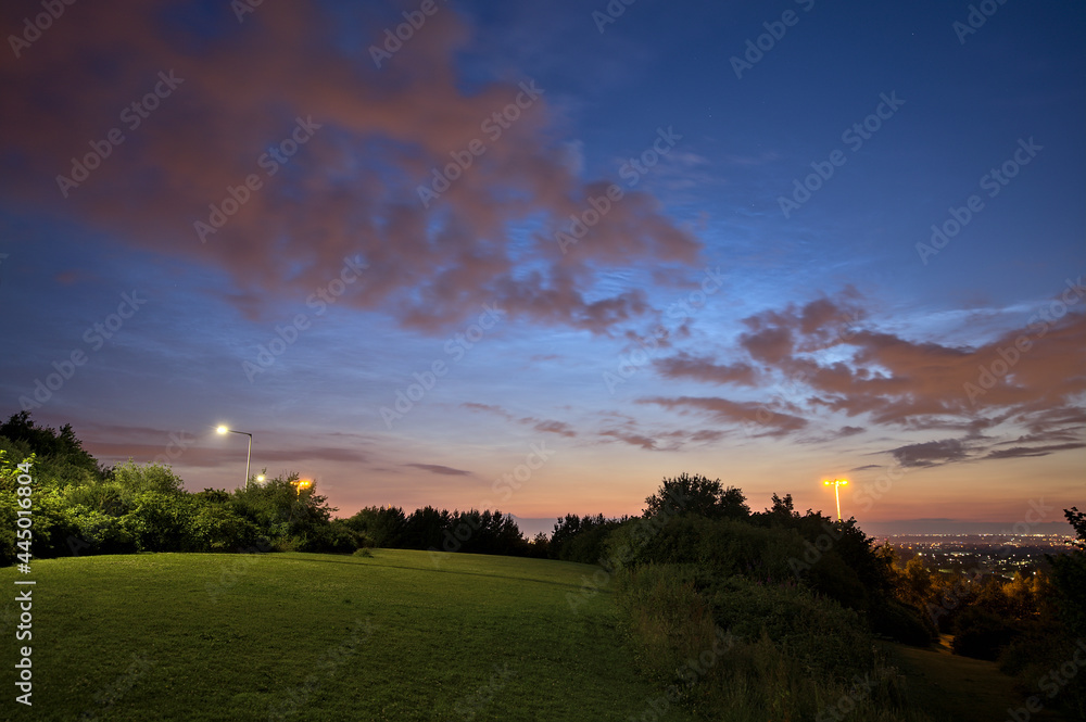 Beautiful wide angle view of very rare noctilucent clouds and common clouds seen in Dublin, Ireland on July 12, 2021 a half of hour before midnight. Details of NLC. Night shining clouds. Crescent Moon