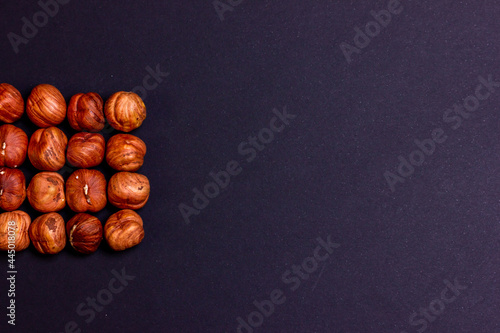 Hazelnut close-up on a black background. The texture of fresh hazelnuts. Free space for the inscription. Hazelnuts folded in the form of a square.