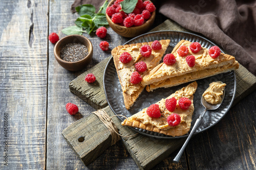 Summer sweet dessert sandwich breakfast. Tasty toasted with peanut butter and raspberry on a rustic wooden table. Copy space.