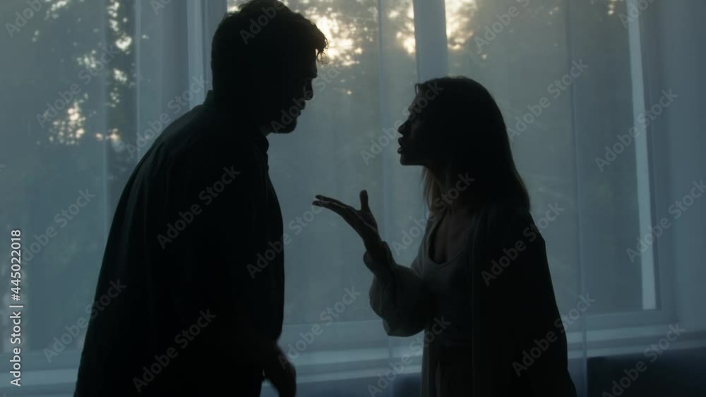 Silhouettes of man and woman shouting at each other, couple quarreling in the evening at home husband and wife screaming. Scandal and crisis in family. Domestic violence, abuse.