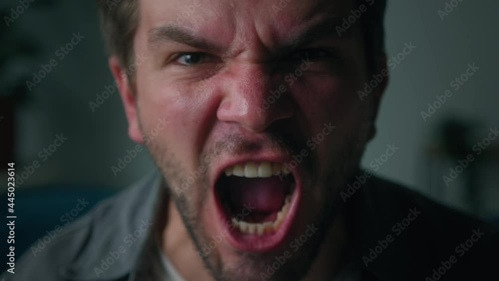 Irritated emotional man shouting close-up, portrait of screaming brutal male person with beard, sitting on sofa in living room, looking in camera with furious view, feeling anger and stress, bad mood. Irritated emotional man shouting close-up, portrait of screaming brutal male person with beard, sitting on sofa in living room, looking in camera with furious view, feeling anger and stress, bad mood.