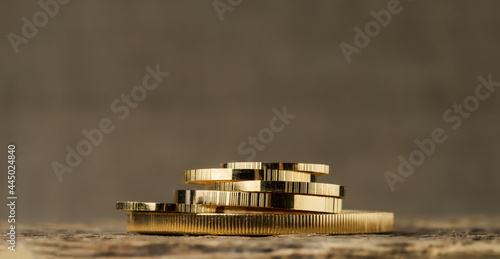 A pile of gold coins of different sizes on a blurred background.