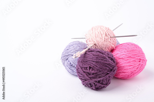 Colorful yarn balls and knitting needles on white background
