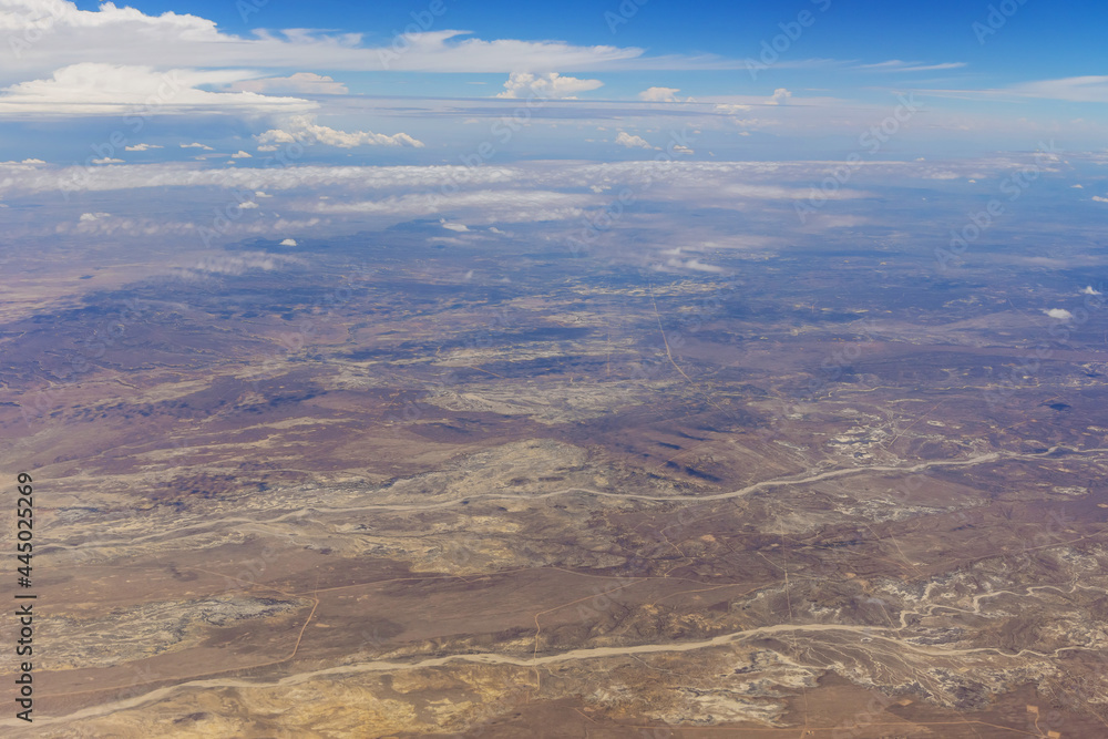 Overview in desert New Mexico from the plane of fluffy clouds in mountains an airplane