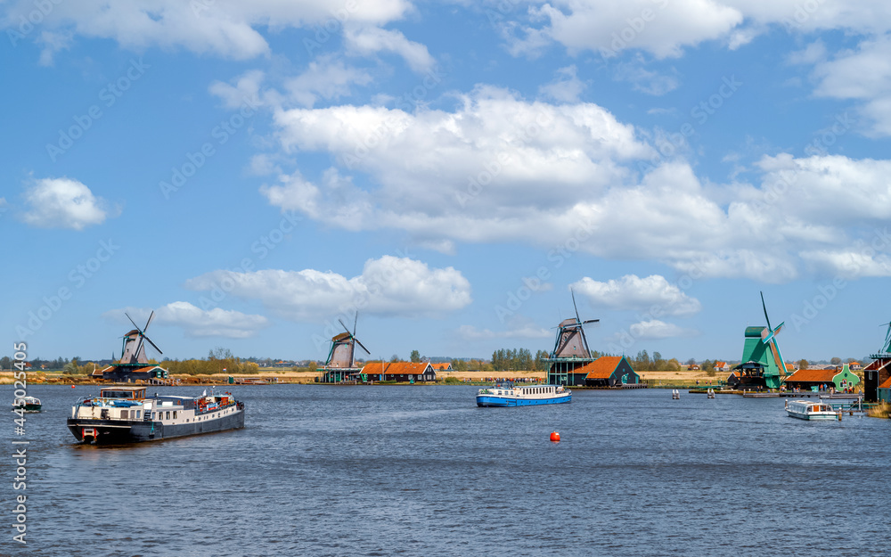 Panoramic view of authentic dutch windmills and ships on the water channel in the historic village of Zaanse Schans, Holland Netherlands.