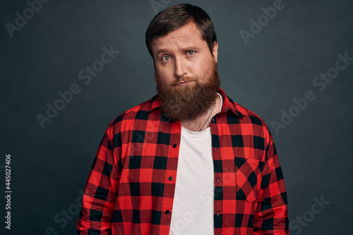 Motivation, people and emotions concept. Serious-looking determined handsome young guy with beard in red checkered shirt, squinting pensive and focused