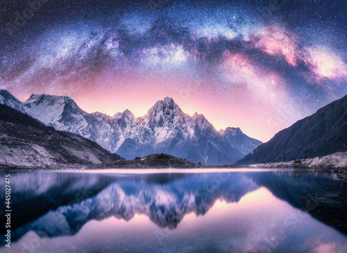 Milky Way over snowy mountains and lake at night. Landscape with snow covered high rocks, purple starry sky, reflection in water in Nepal. Sky with stars. Bright milky way in Himalayas. Space. Nature © den-belitsky