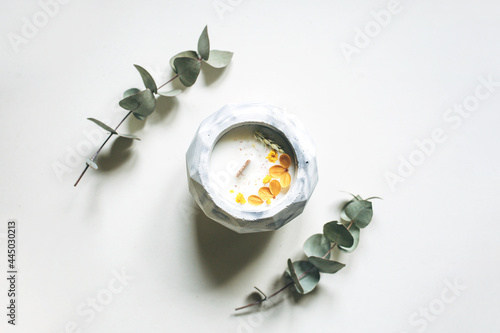 Ecological and vegan handmade candle on a white background with dry flowers in a glass made of concrete. Soy or coconut candle with a wooden wick.