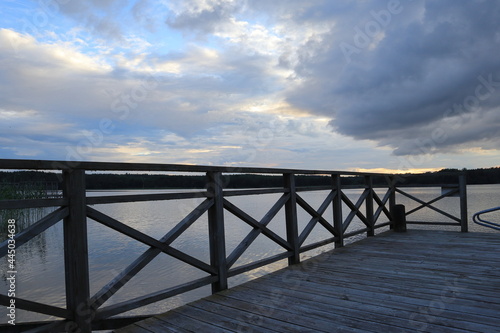 Beautiful view at a Swedish sea or lake. Wooden fence and bridge. Plenty of bugs. Concept of calmness or solitude. Multicolored sky with plenty of clouds. Stockholm, Sweden, Scandinavia, Europe.