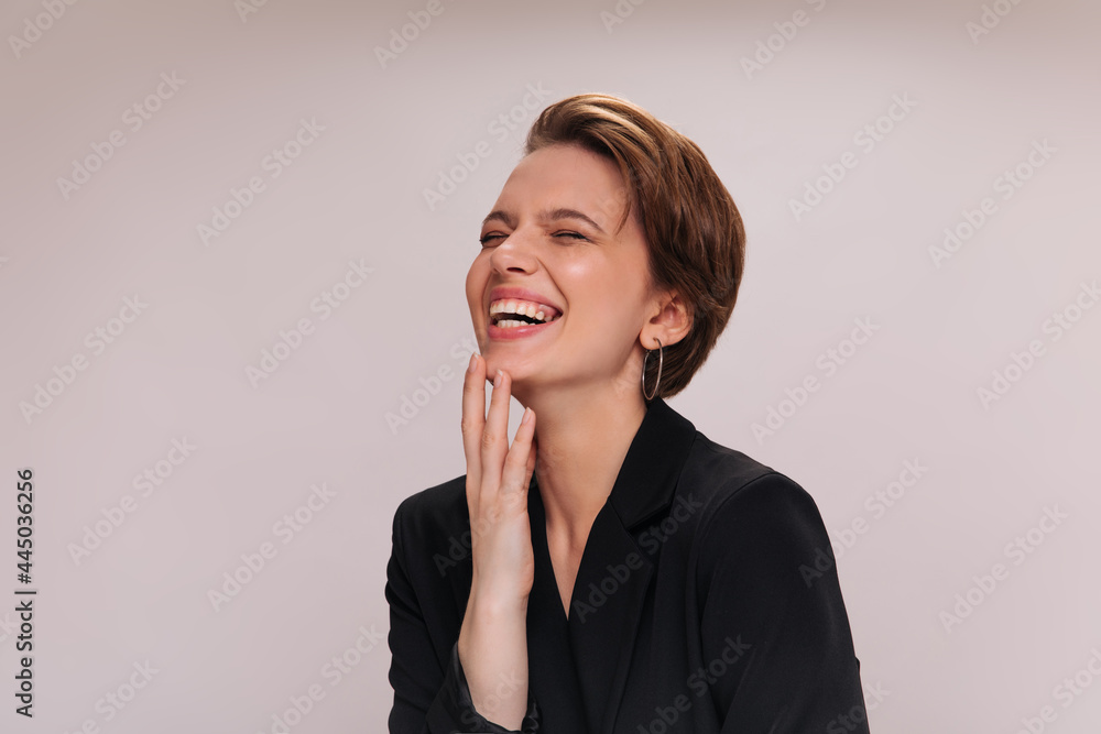 Girl in black jacket laughing on isolated background. Close-up inside portrait of woman in dark suit smiling and posing on white backdrop Girl in black jacket laughing on isolated background. Close-up inside portrait of woman in dark suit smiling and posing on white backdrop