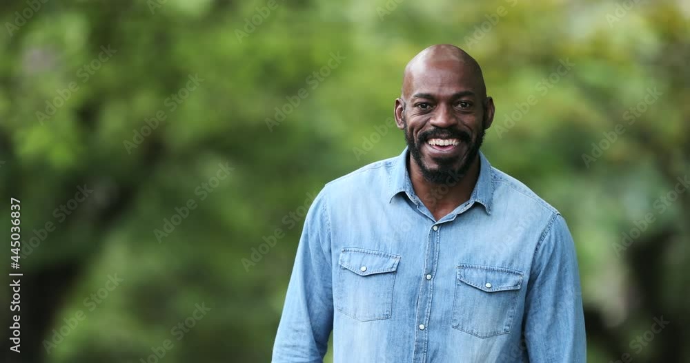 Happy African man smiling outside. Joyful black ethnicity person standing Happy African man smiling outside. Joyful black ethnicity person standing