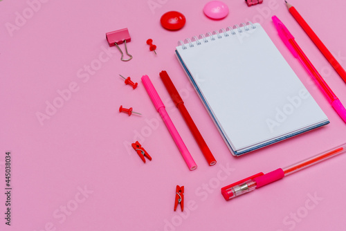Stationery in pastel pink shades. On a pink background, flat lay. Markers and pencils with pens, spiral notebook top view. Copy space.