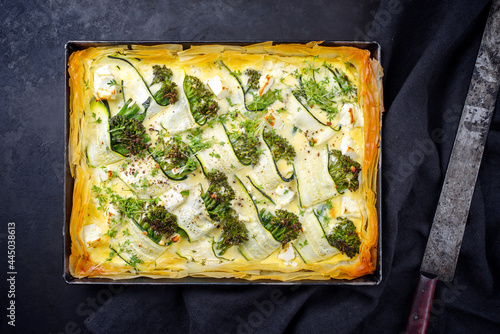 Traditional French Tarte with zucchini and baby broccoli served as top view in backing form with copy space