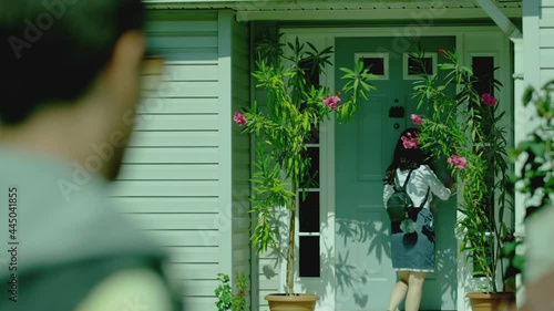 Back rear view stranger man following young girl while she walking on way to home . Girl opens door and enters inside house  boy secretly follows , spying behind . Boyfriend tracking of his girlfriend