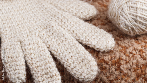 Close-up of crocheted wool glove, natural color, with ball of wool. Single crochet stitch. © Ri Fotoproducto