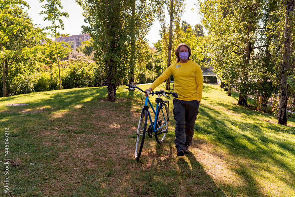 Obraz premium Man walking in the park with his bicycle