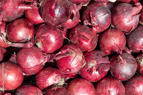 Selective focus of unpeel red onions on the market stall, Cultivars of the onion (Allium cepa) with purplish-red skin and white flesh tinged with red, Texture background.