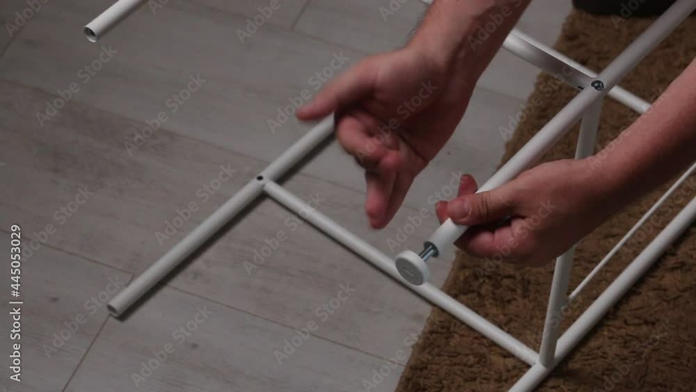 The man collects the rack. Installs the legs in the metal shelf. Close-up shot. Homework during self-isolation. The man collects the rack. Installs the legs in the metal shelf. Close-up shot. Homework during self-isolation.