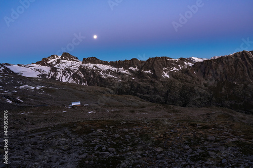 Nighttime with shining moon over a valley in the alps.