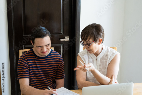 Adult mature mom helping young son with online home school