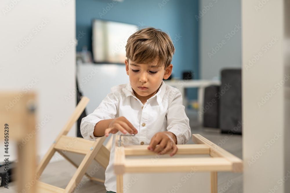 Small caucasian boy four years old playing with self assembly chair or table on the floor at home in day - little child assembling furniture alone childhood craft concept front view copy space Small caucasian boy four years old playing with self assembly chair or table on the floor at home in day - little child assembling furniture alone childhood craft concept front view copy space