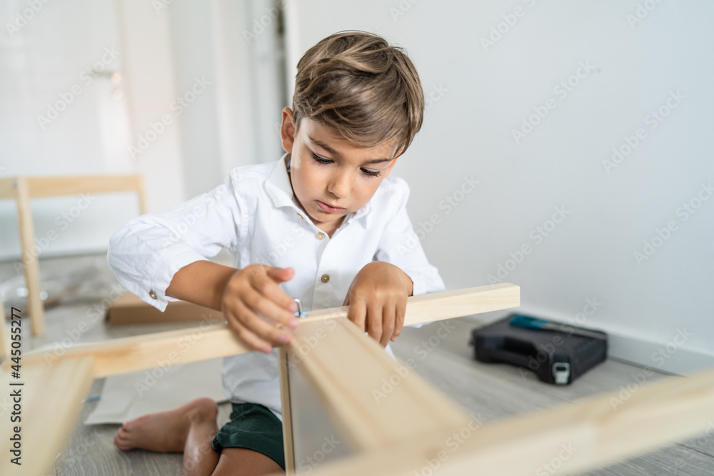 Small caucasian boy four years old playing with self assembly chair or table on the floor at home in day - little child assembling furniture alone childhood craft concept front view copy space Small caucasian boy four years old playing with self assembly chair or table on the floor at home in day - little child assembling furniture alone childhood craft concept front view copy space