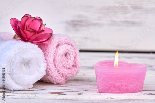 Rolled towels with burning candle on white background.