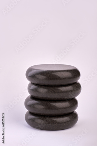 Vertical shot stack of black stones on white background.