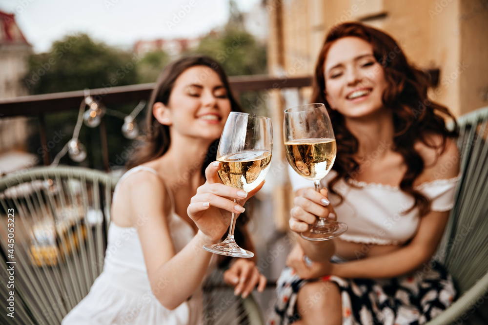 Attractive women enjoy good day with wine on terrace. Lovely girls in great mood have fun and pose for camera Attractive women enjoy good day with wine on terrace. Lovely girls in great mood have fun and pose for camera